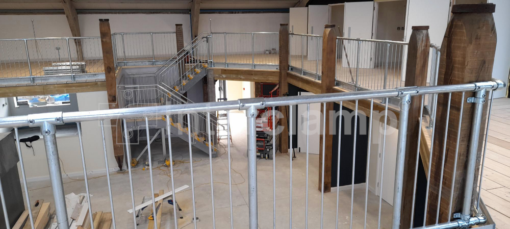 Second-floor mezzanine equipped with Interclamp pedestrian barriers and tube clamp fittings, creating a reliable fall protection barrier for an indoor space.